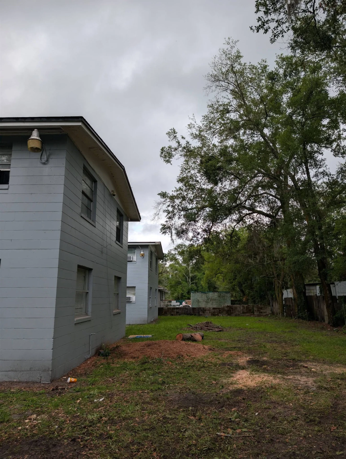 The same apartment building after the tree was removed, with ground stump mulch spread across the open lawn